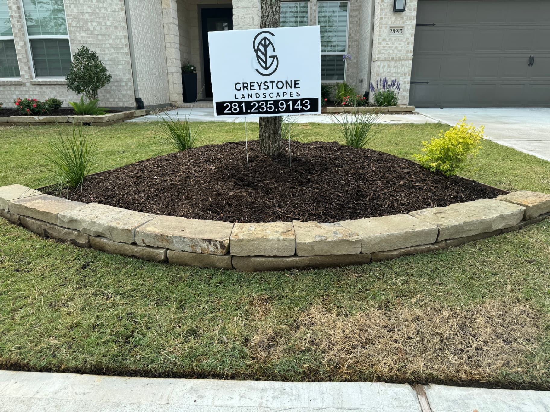 Greystone Landscapes yard sign with stone edging and mulch